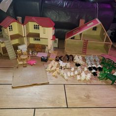 doll houses and books on the floor in front of a couch