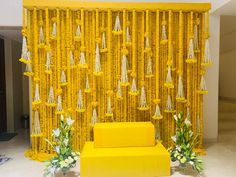 a yellow couch sitting in front of a wall with tassels on it