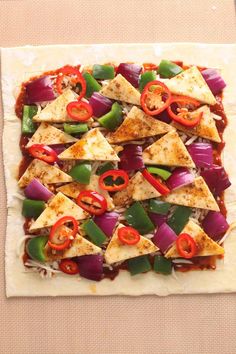 the pizza is topped with cheese, peppers, and tofu slices on parchment paper