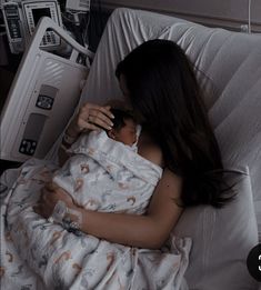 a woman wrapped up in a blanket laying on a bed next to an iv machine