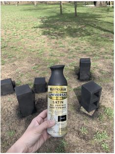 someone is holding up a bottle of paint in front of some black cubes on the ground