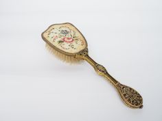 Antique Brass Vanity Brush | Mid 20th Century | Old Vintage Hair Brush | Victoria Style | Flower Embroidered Fabric | Decorative Handle Length: 10 in / 25.3 cm Height: 1.5 in / 3.5cm Width: 3.3in / 8.5cm Beautiful antique vanity brush with a detailed brass handle, delicate flower embroidered fabric on the head and a smooth wood finish with stiff nylon bristles.  The item is in very good condition for its age, dated to sometime in the 1950's. The brush has a few small patina stains on the floral embroidered fabric. (See photos) This piece would make a great addition to any bedroom chamber décor.  Feel free to message us with any questions you may have. Old Hairbrush, Antique Hair Brush, Vintage Hair Brush, Victoria Style, Boar Bristle Hair Brush, Brass Vanity, Victoria Fashion, Antique Vanity, Brass Handle