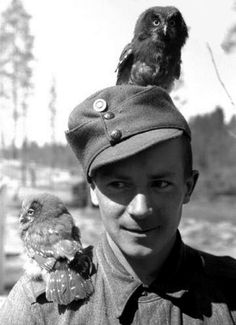 a boy in uniform holding an owl on his shoulder and looking at the camera man's face