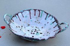 a white and blue bowl sitting on top of a table next to a red flower