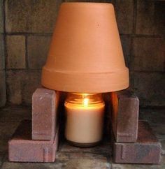 a lit candle sitting in front of a brick wall with blocks around it and a clay lamp on top