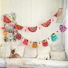 a dog laying on top of a white couch next to pillows and decorations hanging from the wall