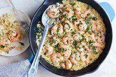 a skillet filled with shrimp and rice next to a plate of food on a table