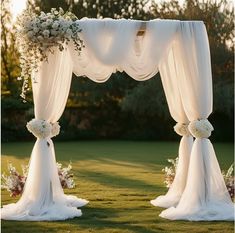 an outdoor wedding ceremony with white drapes and flowers