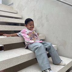 a little boy sitting on some stairs smiling