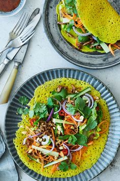 two plates filled with tacos and salad on top of a table