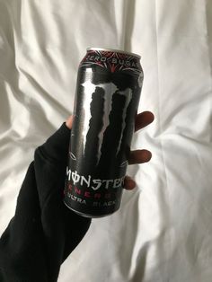 a person holding up a can of monster energy