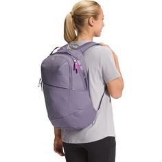 a woman wearing a purple backpack with her back turned to the camera and looking down