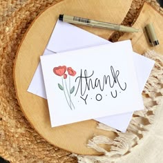 a thank you card sitting on top of a table next to a straw hat and pen