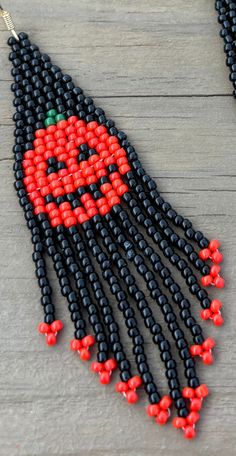 beaded earrings with red and black beads hanging from them on a wooden surface,