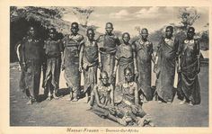 a group of african men standing next to each other on a dirt road with trees in the background