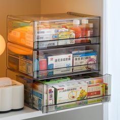 three clear containers are stacked next to each other on the shelf in front of a lamp