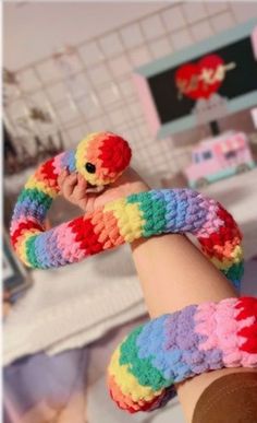 someone is holding their hand up to the camera and wearing colorful crocheted socks