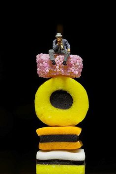 a man sitting on top of a stack of doughnuts that are yellow and black