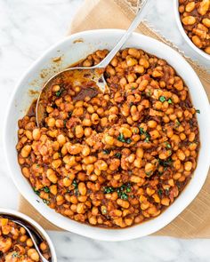 two bowls filled with baked beans on top of a table