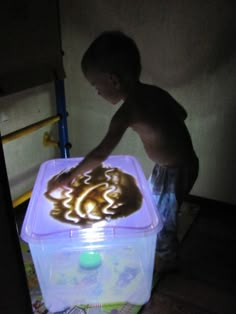 a young boy standing next to a plastic container