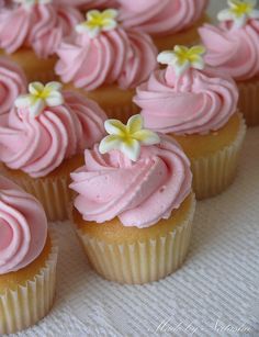 cupcakes with pink frosting and white flowers on top are arranged in rows