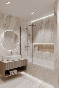 a bathroom with marble walls and flooring is pictured in this image, it has a large round mirror on the wall above the bathtub