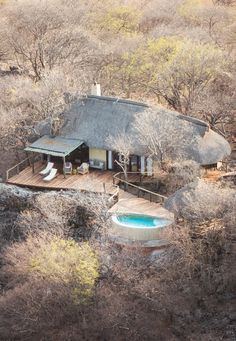 an aerial view of a house with a pool in the foreground and trees surrounding it