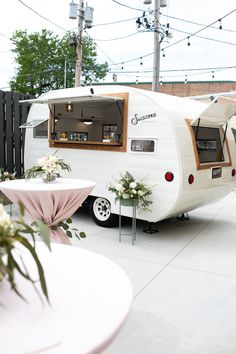 a white trailer parked next to a table with flowers on it