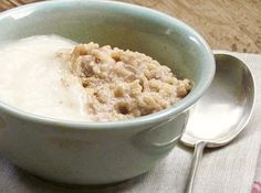 a bowl filled with oatmeal sitting on top of a table next to a spoon