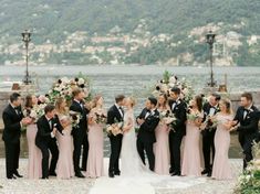 a group of people standing next to each other in front of a body of water