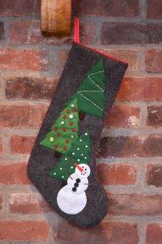 a christmas stocking hanging on a brick wall with a snowman and tree decoration