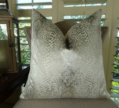 a close up of a pillow on a chair in front of a window with shutters