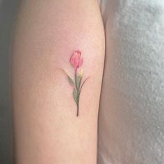 a small pink flower tattoo on the arm