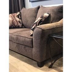 a brown couch with pillows on it in front of a window