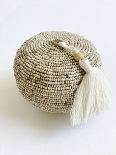 a round woven bag with tassels on top