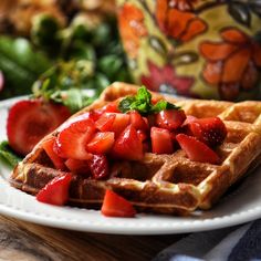 waffles topped with strawberries and mint on a plate