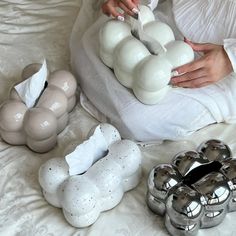 a woman is sitting on a bed with some decorative objects