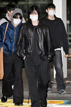 two men wearing masks walking down the street together, one man has his hand in his pocket