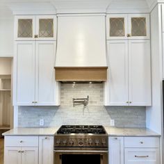 a stove top oven sitting inside of a kitchen next to white cupboards and drawers