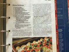 the recipe book is open to show an image of a casserole with olives and tomatoes