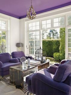 the living room is decorated with purple and white furniture, along with a chandelier