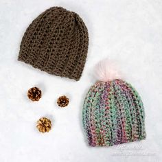 a knitted hat, two pine cones and one ear piece are laying on the snow