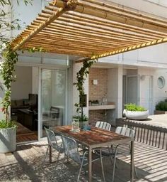 an outdoor table and chairs under a wooden pergolated awning on a patio