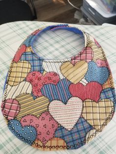 revertible baby bib in a colorful heart patch work pattern in cotton on one side and blue flannel on the other side.   this bib closes with velcro and is edged with a x stitch.  This bib is washer/dryer friendly Multicolor Cotton Bib, Machine Washable, Cute Multicolor Machine Washable Bib, Cute Handmade Cotton Bib, Blue Cotton Bib For Playtime, Cute Blue Bib For Playtime, X Stitch, Heart Patch, Work Pattern, Blue Flannel