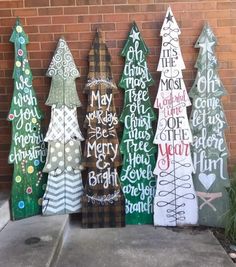 wooden christmas trees are lined up against a brick wall with words painted on the boards