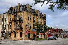 an old brick building on the corner of a street with cars parked in front of it