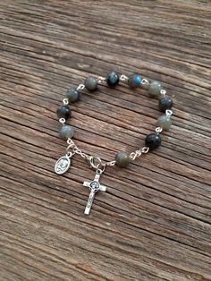 "Beautifully made Rosary bracelet! Beads are 8mm polished Labradorite stone, Cross is a 7/8\" silver St. Benedict crucifix, and mini medal is a 1/2\" mini medal with amazing details **Alternate Mini Medal Choices** 1. Holy Family/Holy Spirit 2. St Michael/Guardian Angel 3. Holy Eucharist and chalice *LOW STOCK* 4. St. Benedict medal 5. 5 way cross 6. Miraculous Mary medal 7. Sunburst cross *LOW STOCK* Each one of my rosary bracelets starts its life as a spool of wire and a handful of beads. It i Rosary Jewelry How To Make, One Decade Rosary Diy, Labradorite Bead Jewelry As A Gift, Adjustable Silver Rosary Bracelet With Gemstone Beads, Spiritual Silver Rosary Bracelet With Natural Stones, Silver Rosary Bracelet With Gemstone Beads, Silver Rosary Bracelet With Natural Stones As Gift, Silver Rosary Bracelet With Gemstone Beads As Gift, Silver Rosary Bracelet With 8mm Beads For Healing