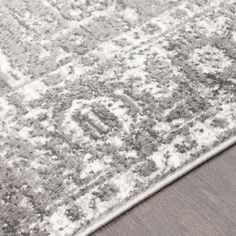 a gray and white rug on top of a wooden floor with an area rug in the middle