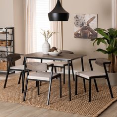 a dining table with four chairs and a plant in the middle on top of a rug