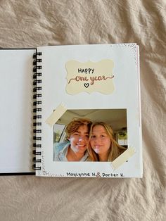 an open photo book with two people in the middle and happy one year written on it